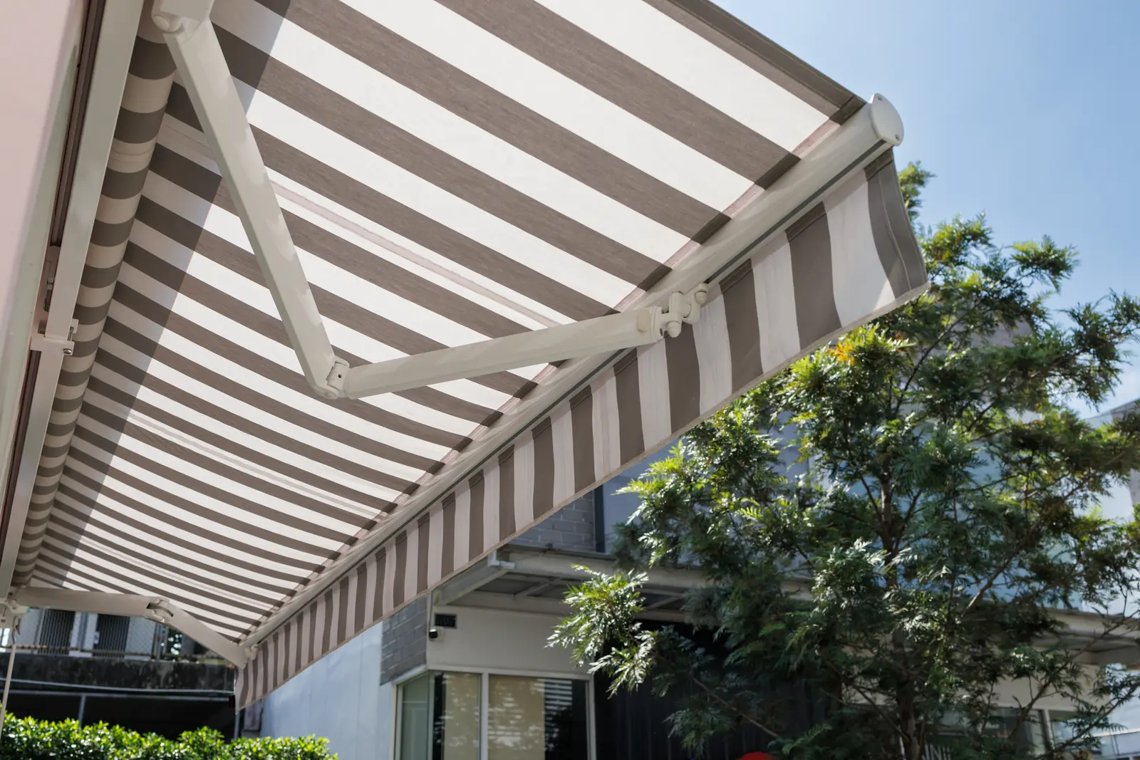 Detalle de la guía lateral de un toldo con la tela tensada por el viento.